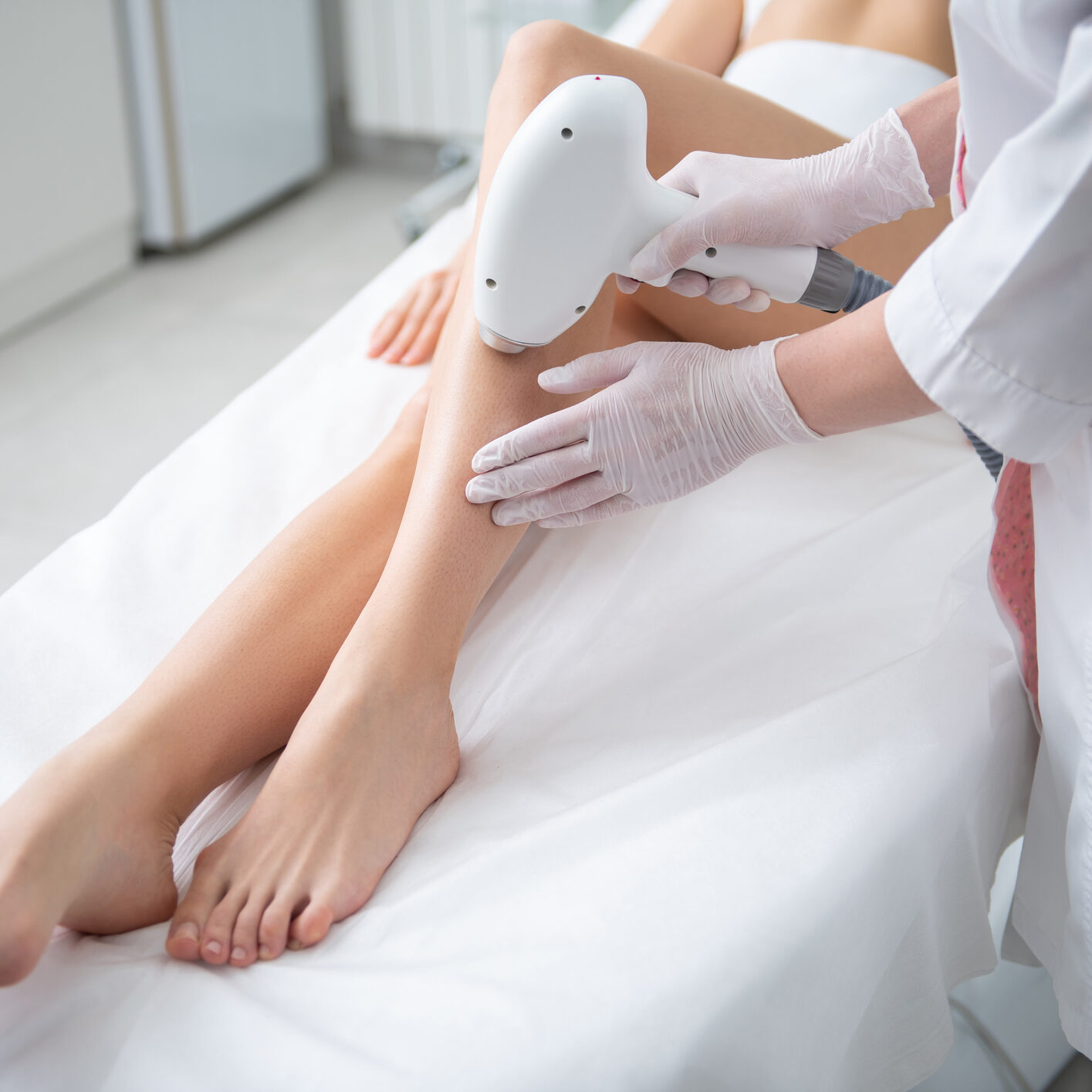 Aesthetic body treatment. Top angle portrait of young slender woman having professional laser hair removal procedure of legs